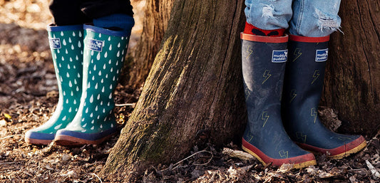 Children wearing colorful waterproof wellies outdoors in a forest setting