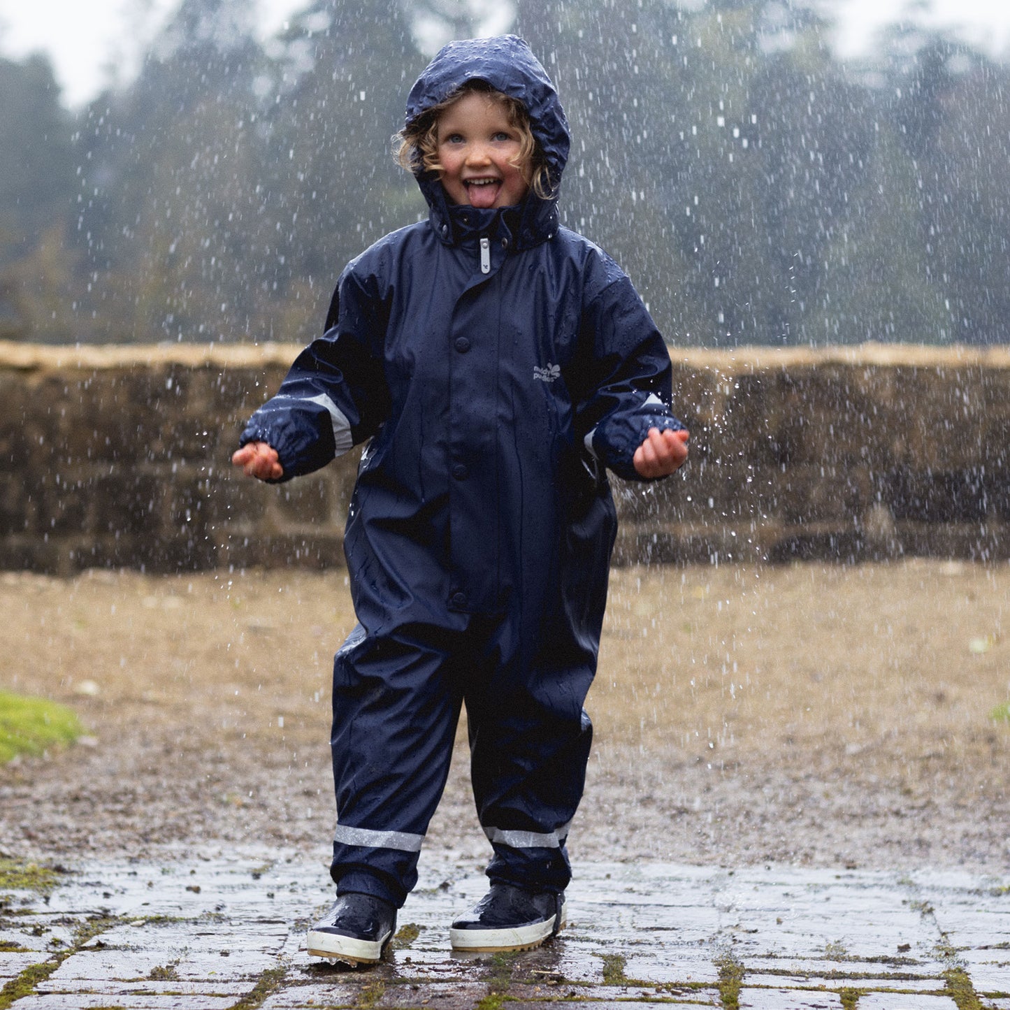 a young girl dancing in the rain wearing puddeflex kids waterproof puddle suit