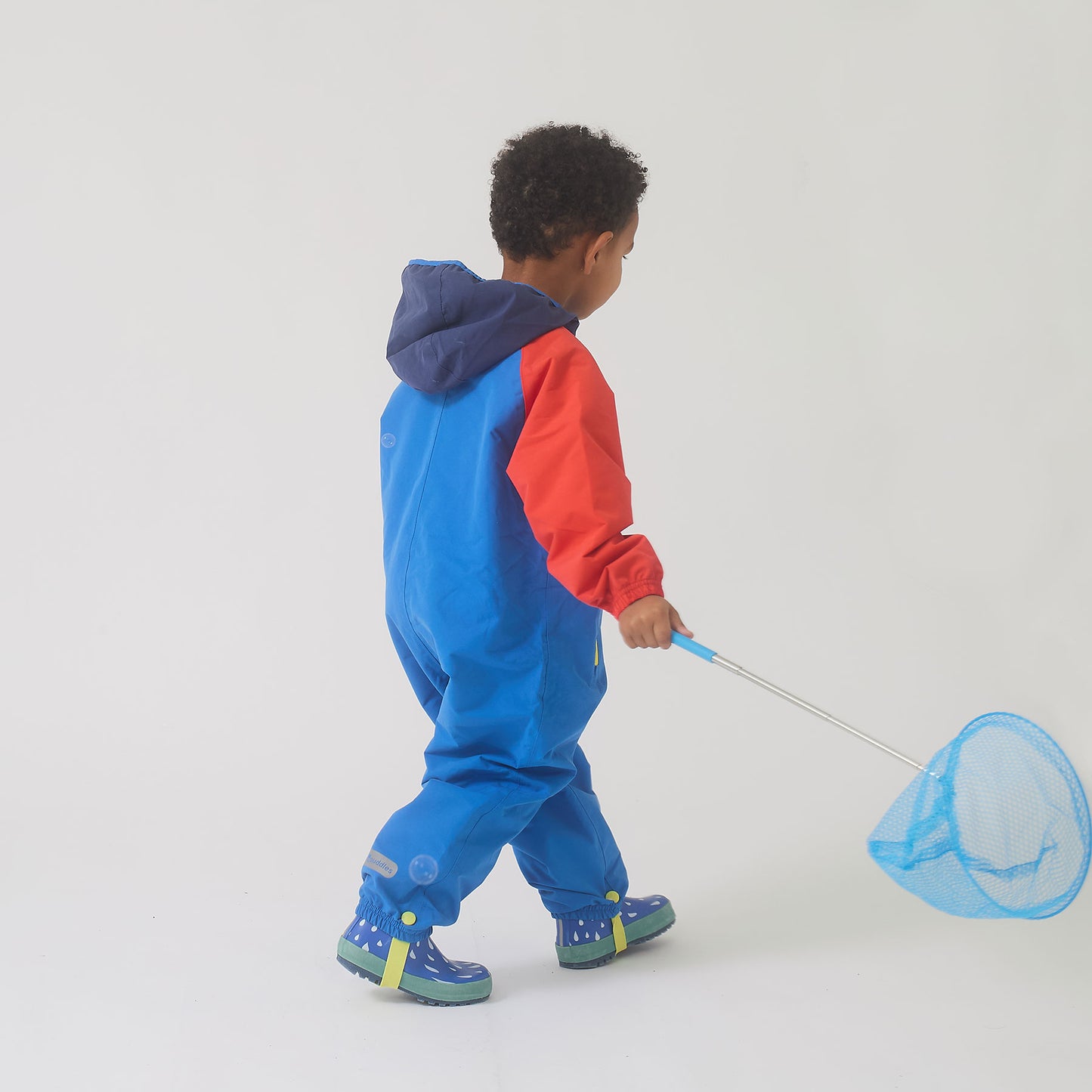 Child wearing EcoLight Lightweight Waterproof Puddle Suit Blue Colourblock, holding a net, showcasing durable, waterproof gear designed for active, rain-filled adventures.