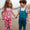 Two children wearing EcoLight Waterproof Dungarees Green Snake stand on a beach. The durable, waterproof overalls feature playful patterns, ideal for adventurous, weather-resistant play.