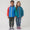Two children wearing Muddy Puddles EcoLight Lightweight Waterproof Jacket Green Snake, smiling and holding hands, showcasing durable, waterproof outerwear ideal for adventurous play in wet weather.